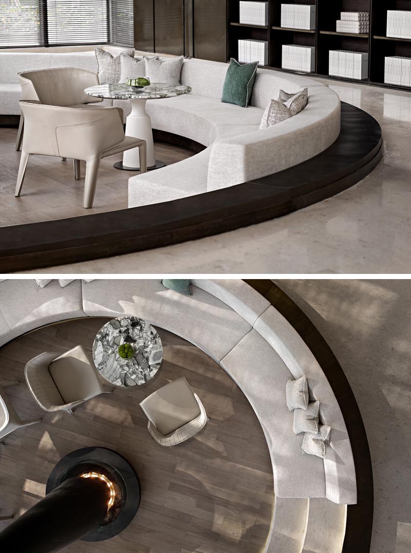 This sunken conversation pit, which was designed as a warm and pleasant space for potential customers to talk, offers custom seating that wraps around the interior of the circular shape, with enough room for small tables to also be included. #ConversationPit #SunkenSeating #InteriorDesign #Fireplace